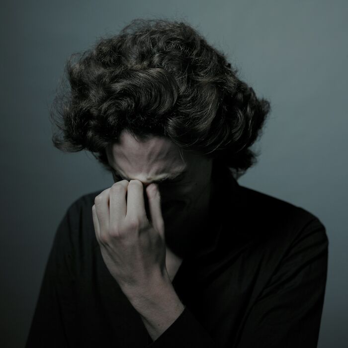 Man with curly hair in dark clothing expressing grief, representing emotional moments in worst and craziest funeral stories.