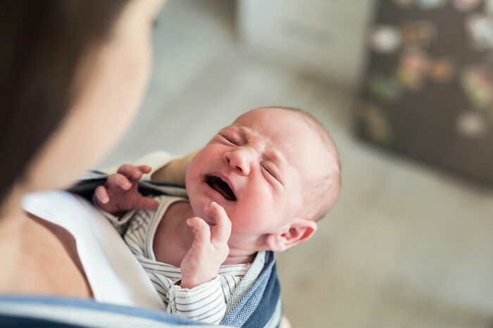 Newborn baby crying in mother’s arms illustrating the impact of medical neglect on families today.
