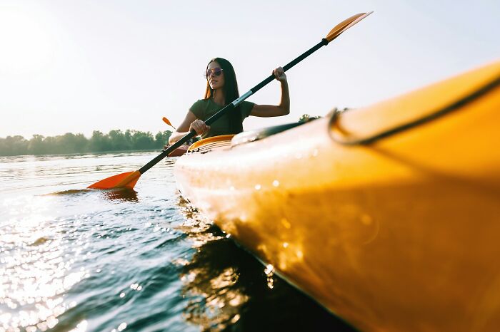 Woman kayaking on calm water at sunset, a peaceful moment related to near-death experiences and how they happened