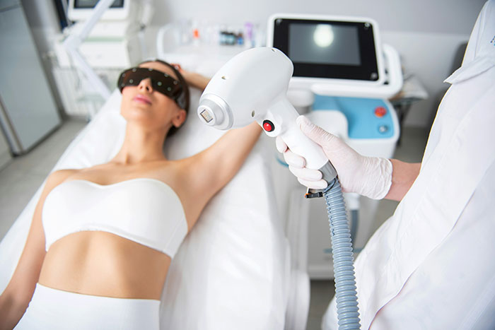 Woman in white bandeau undergoing cosmetic laser treatment, representing husband unattracted plastic surgery wife concerns.