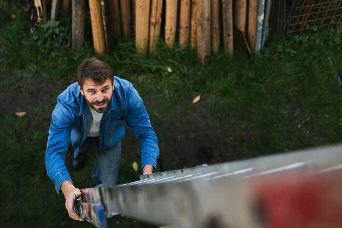 Man climbing a ladder outdoors.