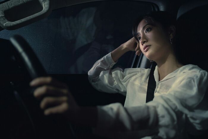 Woman sitting in car at night looking thoughtful, illustrating moments the universe protected people from harm.