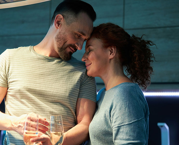Couple sharing a tender moment indoors with drinks, highlighting husband unattracted plastic surgery wife relationship tensions.