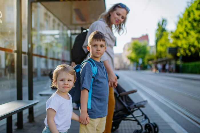 Mother and two children holding hands at a bus stop, highlighting moments before near-death experiences happened.