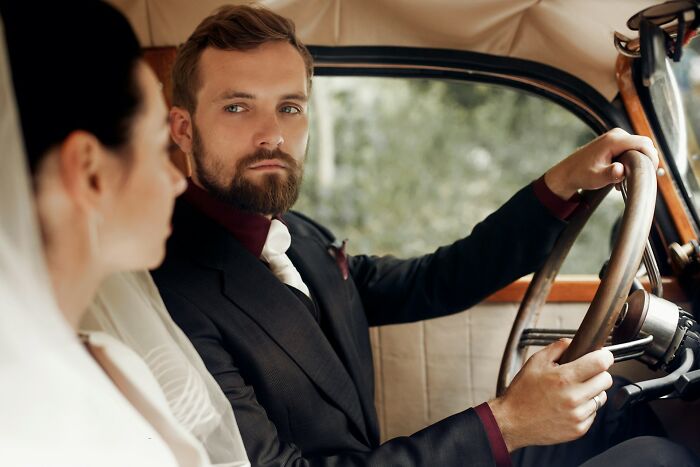 Bride and groom sitting in a car with serious expressions, highlighting wedding guests regrets during the event.