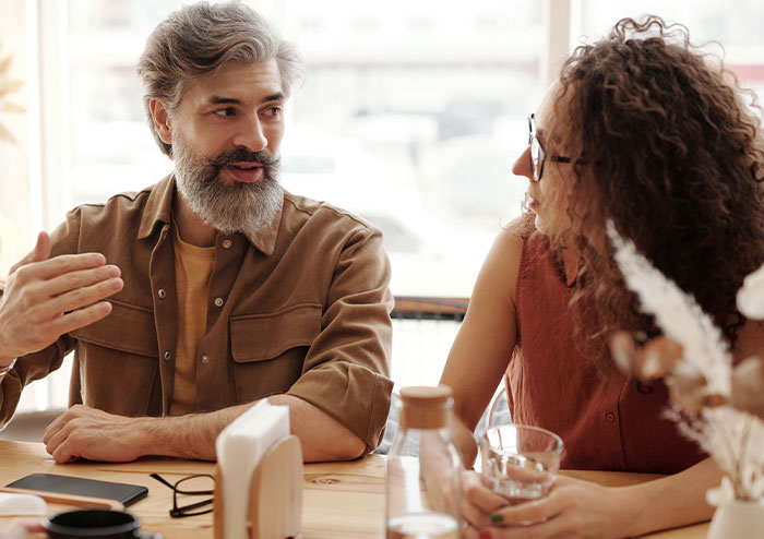 Couple having a serious conversation at a table, woman showing signs of ending her 2-year relationship. Couple having a serious conversation at a table, woman showing signs of ending her 2-year relationship.