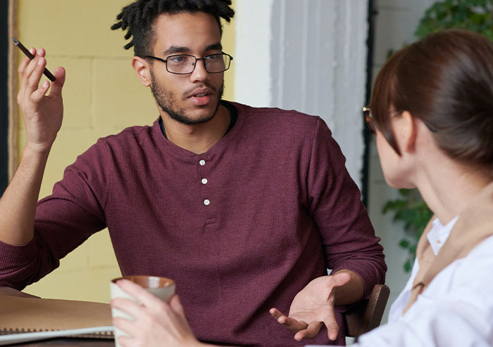 Young man discussing relationship troubles with woman, highlighting plans involving a birthday cruise trip Young man discussing relationship troubles with woman, highlighting plans involving a birthday cruise trip