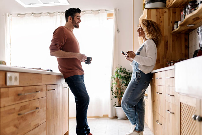 Man and woman in kitchen having a tense conversation, related to man kicking out girlfriend after secret invite of ex.