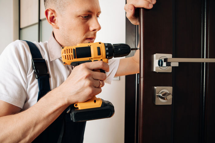 Man using power drill to secure door lock, symbolizing man kicking out girlfriend and her 9-year-old son from house.