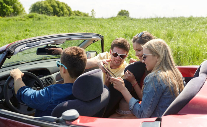 Four young adults in a convertible car on a trip, highlighting relationship tension over a trip with a female friend.