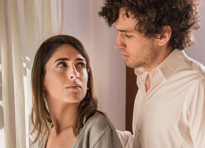 Couple having a tense conversation indoors, woman looking upset while man seems to be reconsidering their relationship.