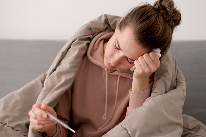 Sick woman wrapped in blanket checking temperature, relating to guy sending homemade food causing her illness. Sick woman wrapped in blanket checking temperature, relating to guy sending homemade food causing her illness.