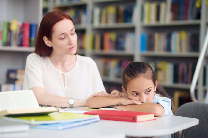Teacher comforting upset child in classroom setting after hermit crab pet issue, highlighting pet care concerns and parental backlash.