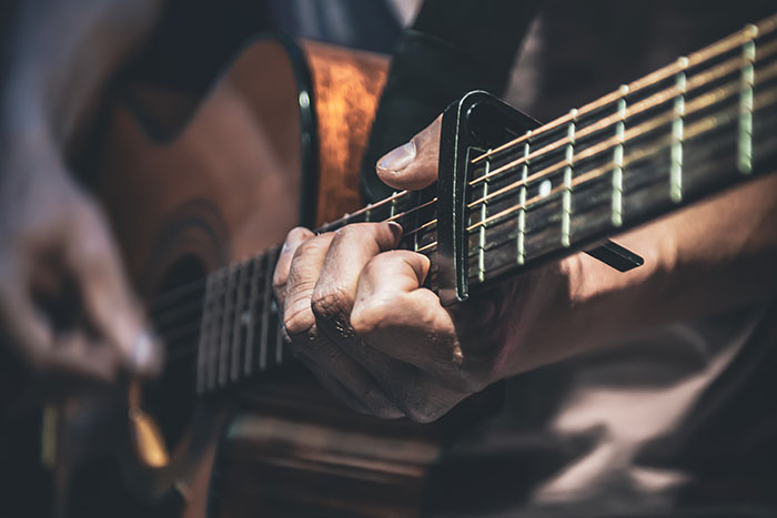 Person playing an acoustic guitar close up, illustrating moments people with famous family members experience discovering fame.