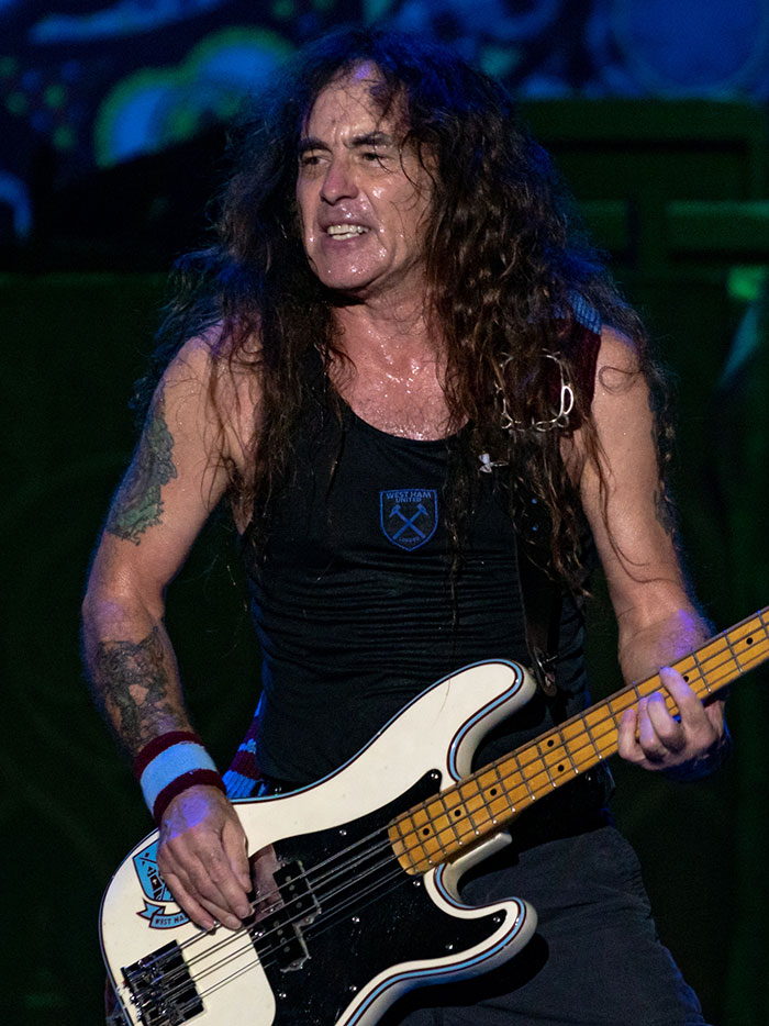 Musician with long hair playing bass guitar on stage, featured in story about people with famous family members.