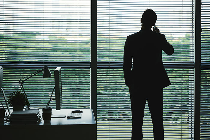 Silhouette of a man making a phone call in an office, reflecting on moments with famous family members.