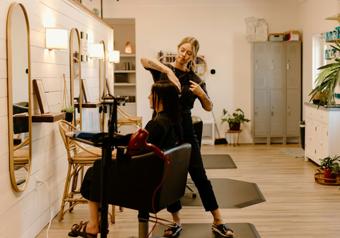 Woman upset friend doesn&rsquo;t give cash but offers a favor instead, shown cutting hair in a salon setting.