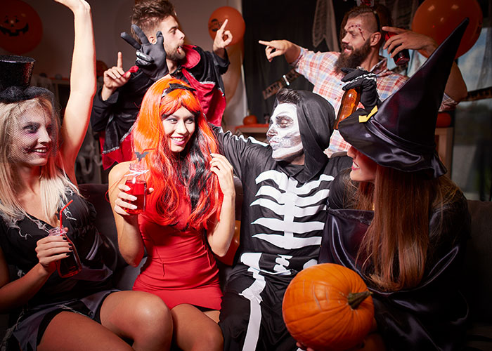 Group of friends in Halloween costumes including skeleton and witch, highlighting masculinity so fragile theme in social setting.
