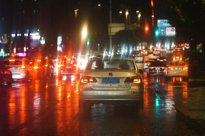 Car on wet road at night with bright city lights reflecting, illustrating near-death experiences in traffic situations.