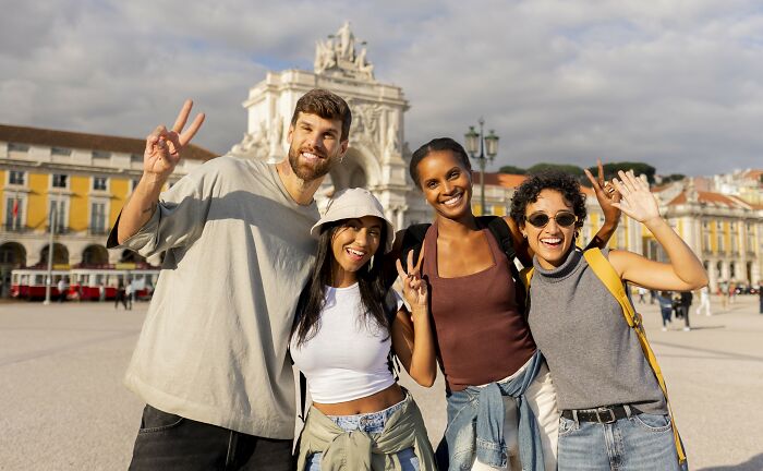 Group of diverse young people smiling and posing happily outdoors, representing positive stereotypes about various countries.