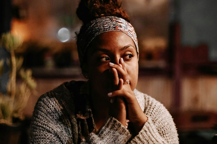 Woman in a headband and sweater reflecting deeply, sharing hardest truths about their lives they had to accept.