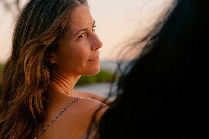Woman reflecting thoughtfully outdoors at sunset, sharing the hardest truths about their lives they had to accept.