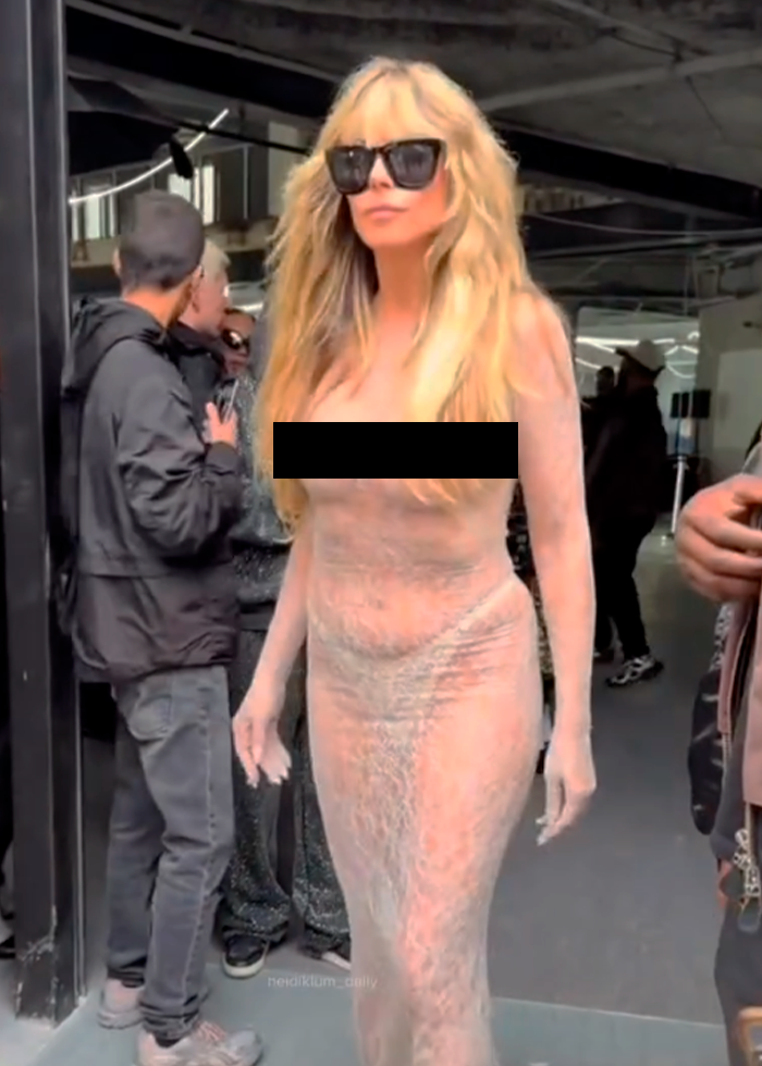 Heidi Klum wearing a fully sheer dress with thong, attending the Vetements Paris show, styled with sunglasses and loose hair.