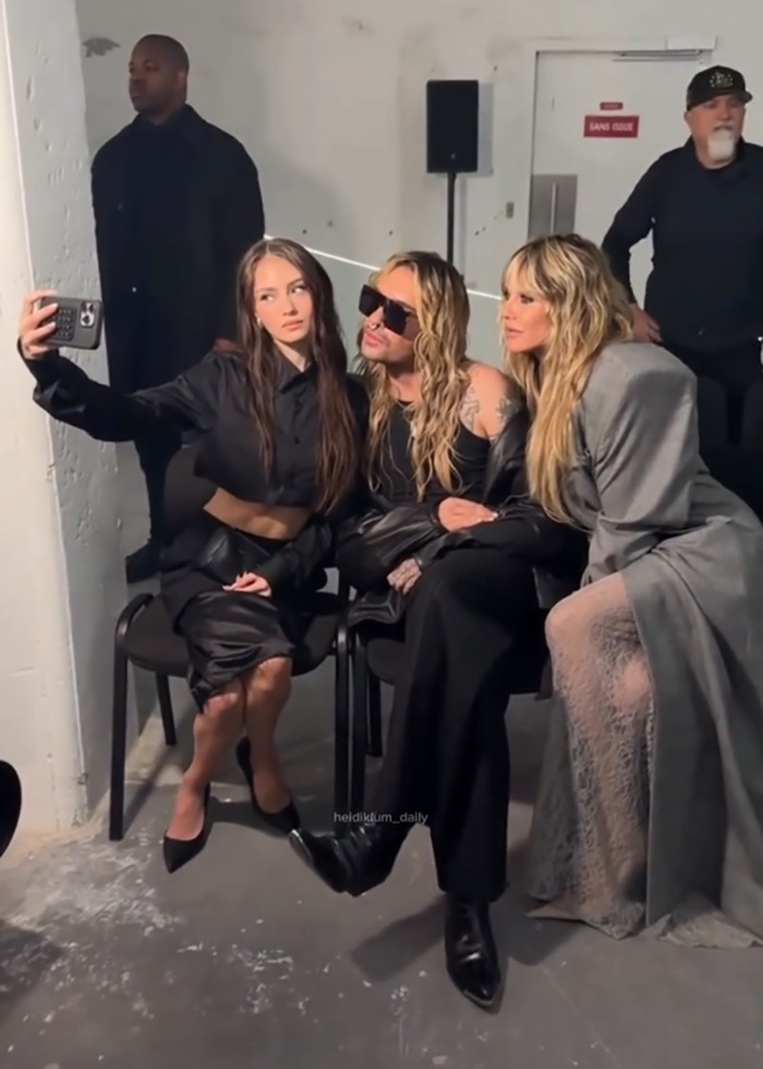Heidi Klum in fully sheer dress with thong posing for selfie with two people at Vetements Paris show backstage.