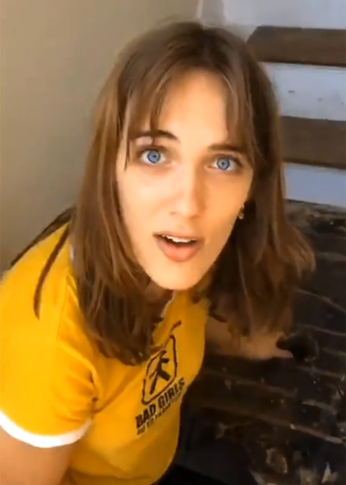 Woman in yellow shirt shows surprise while discovering secret feature hidden under her floor in new home.