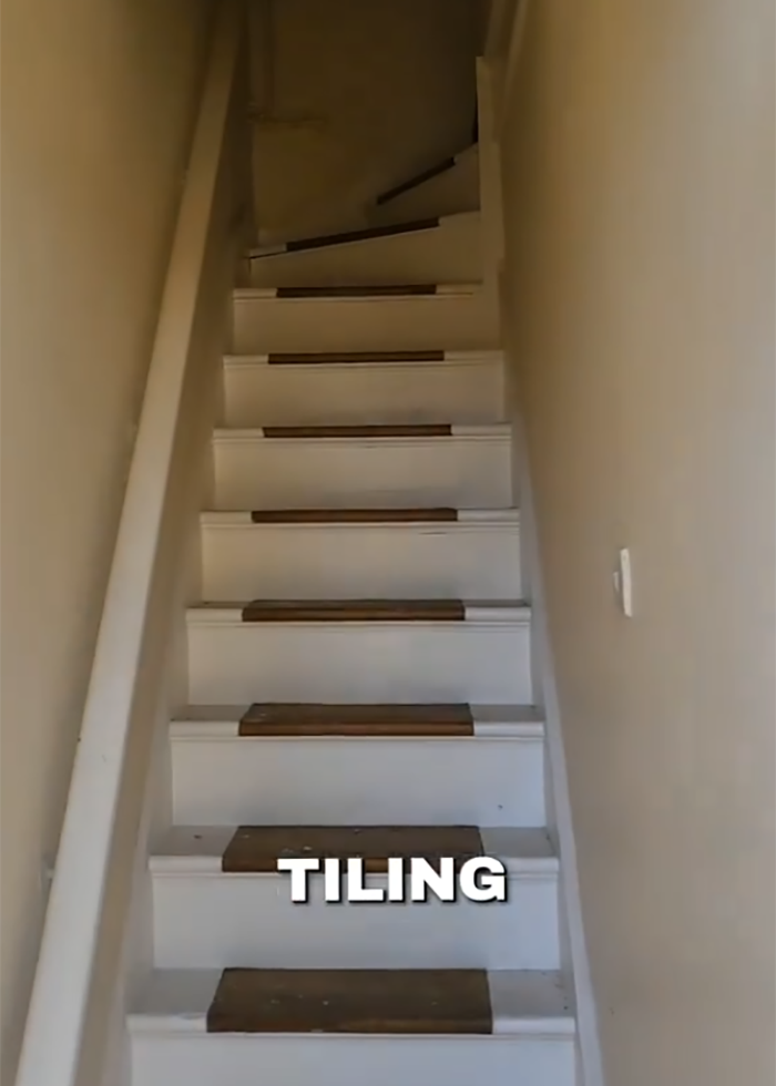 Narrow stairway in a new home indicating a secret feature hidden under the floor discovered by a woman.
