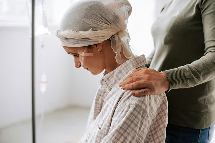 Young woman with headscarf receiving support while undergoing medical treatment in a bright room, reflecting resilience and care.