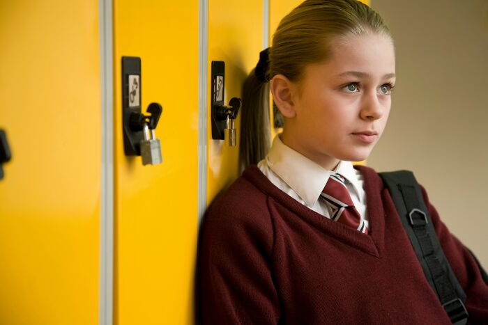 Teen girl in a school uniform standing by yellow lockers, representing memories of the most famous supermodel in the world.