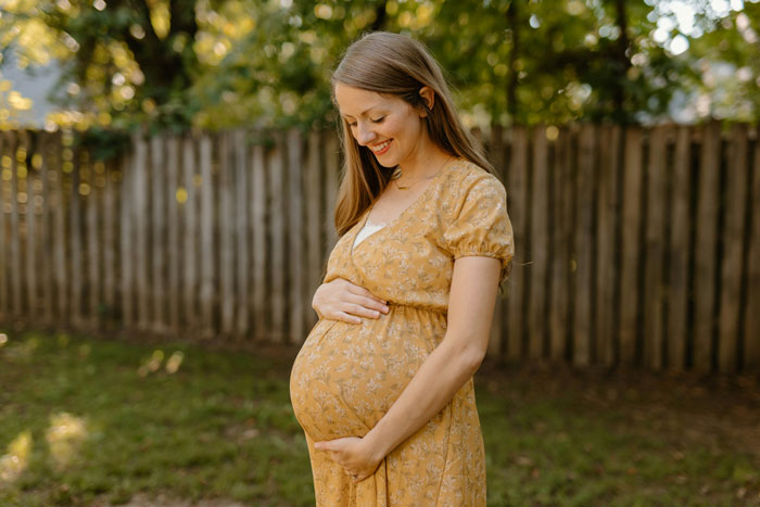 Pregnant woman in yellow dress smiling outdoors, representing heartless ex furious with pregnant wife situation. Pregnant woman in yellow dress smiling outdoors, representing heartless ex furious with pregnant wife situation.