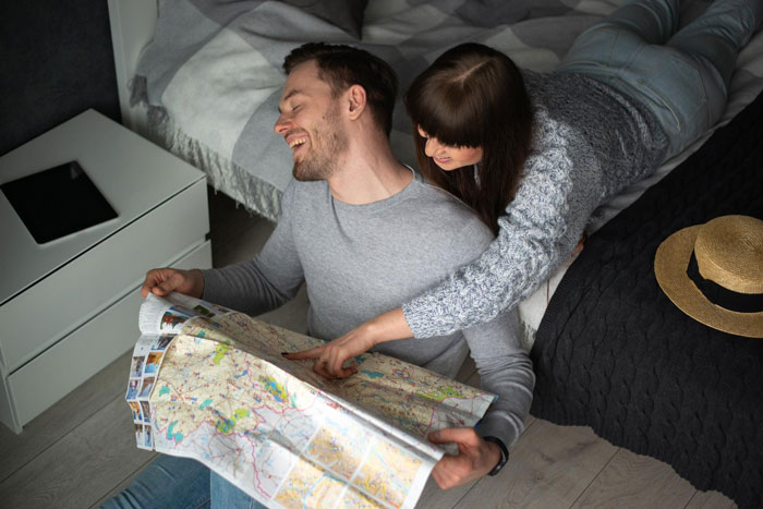 Couple happily planning honeymoon trip together with a map while spending cozy time indoors.