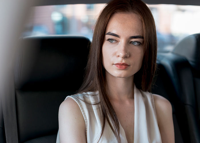 Young woman looking concerned and thoughtful inside a car, reflecting on discovering boyfriend cheating in unusual way.