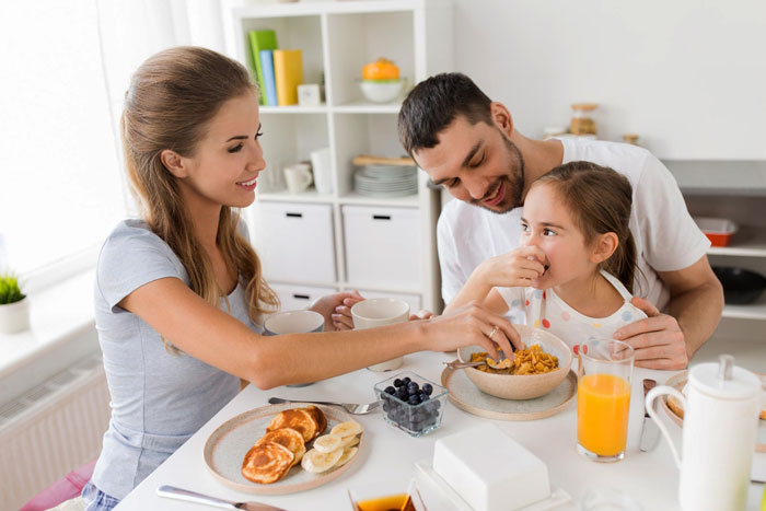 Mom and family sharing breakfast at kitchen table, highlighting challenges of eating together and family mealtime struggles.