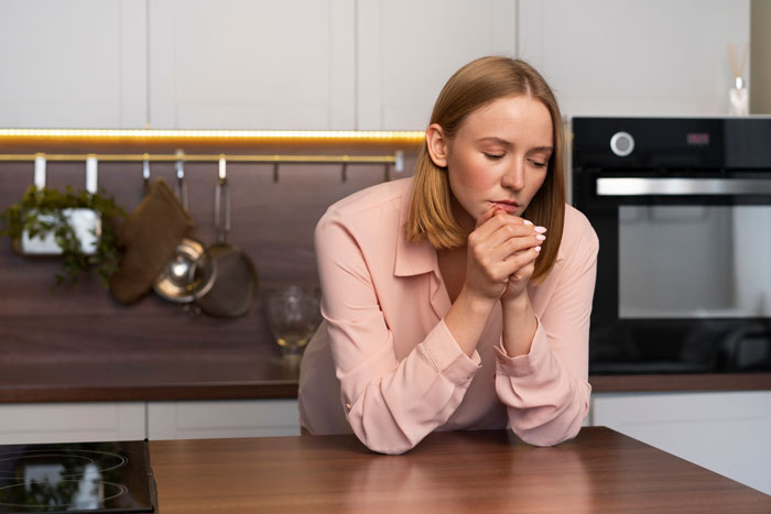 Mom feeling frustrated and thoughtful in kitchen, fighting a losing battle to eat together with family amid challenges.