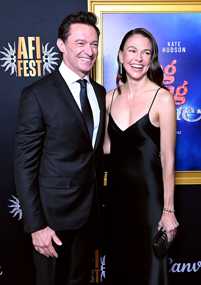 Hugh Jackman and Sutton Foster smiling together on the red carpet amid midlife crisis fan reactions.