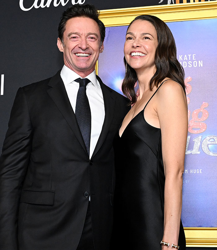 Hugh Jackman and Sutton Foster smiling at a red carpet event, body language experts decode their behavior.