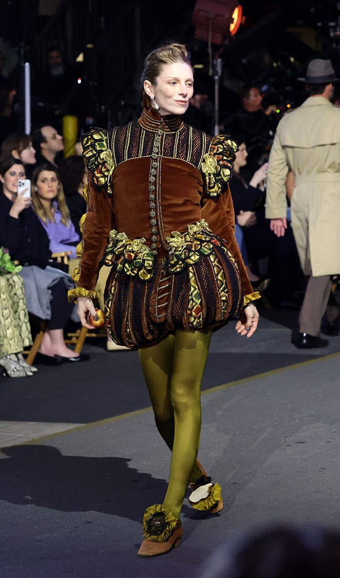 Model walking runway in a bizarre outfit with puffed sleeves and olive tights, highlighting weird celebrity looks Vogue World Hollywood 2025.