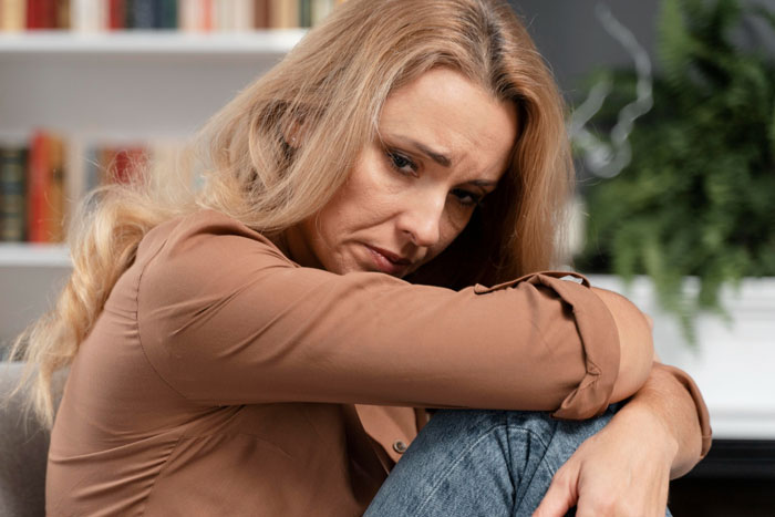 Heartbroken woman sitting alone with a sad expression, reflecting on past pain from husband's affair.