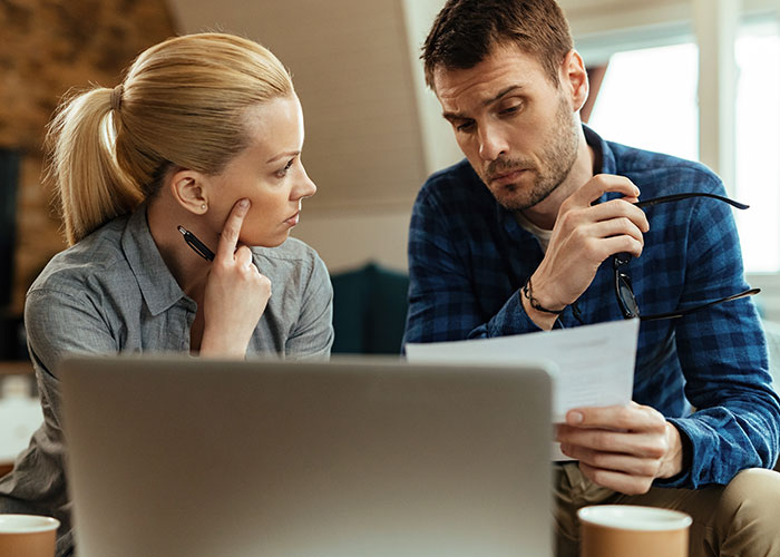 A man and woman looking serious while reviewing documents, illustrating men sharing icks that cause loss of interest.