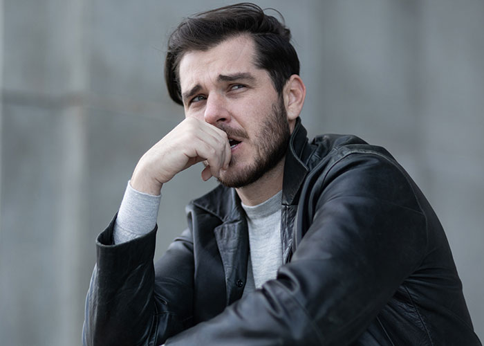 Man in a black leather jacket looking thoughtful and concerned, representing men sharing icks that cause loss of interest.