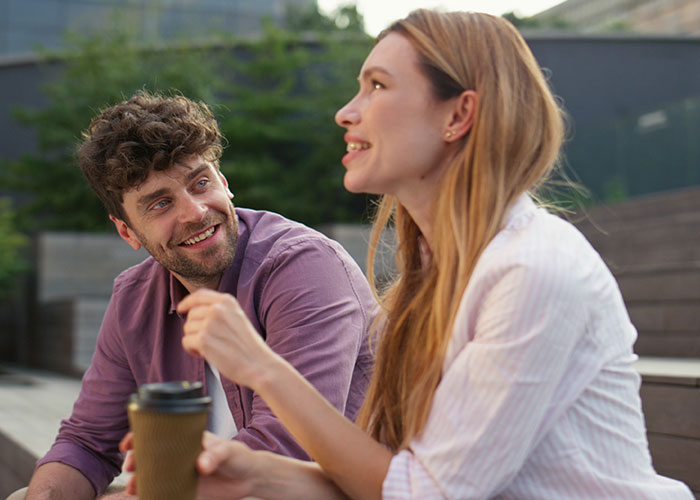 Young man and woman having a casual outdoor conversation, illustrating men sharing what icks make them lose interest in women.