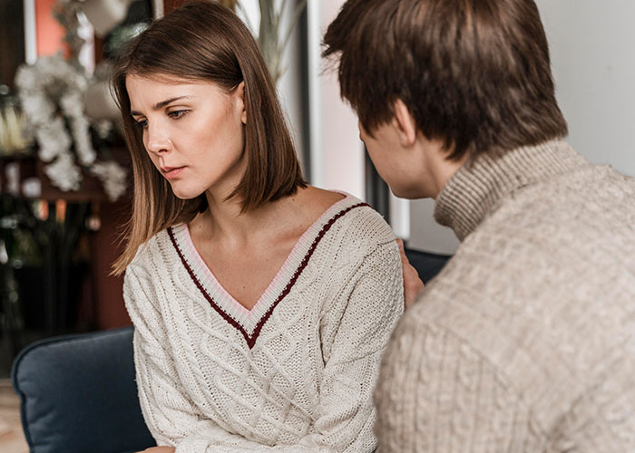 Couple in serious conversation indoors, illustrating common icks that make men lose interest in a woman.