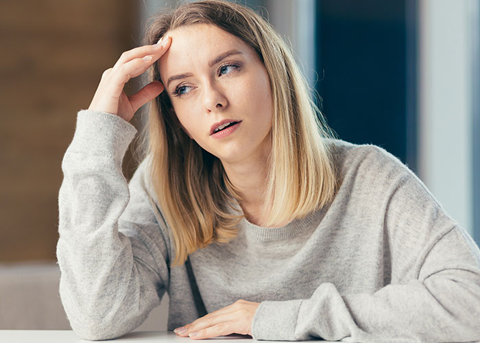 Young woman with a concerned expression, wearing a gray sweater, illustrating icks that make men lose interest in women.