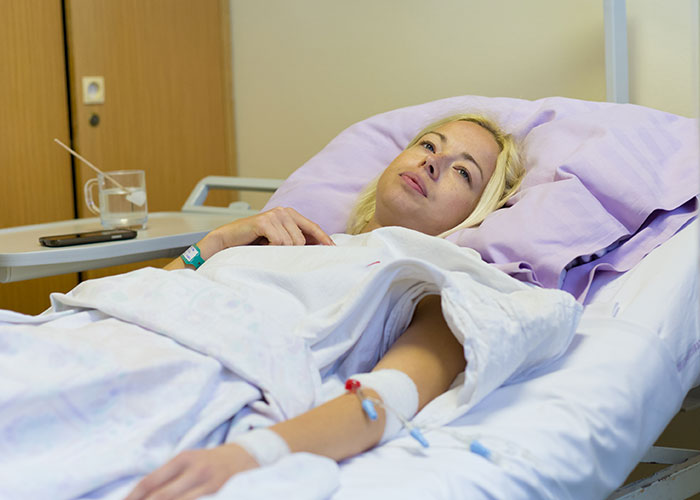 Woman lying in hospital bed looking contemplative, depicting icks that make men lose interest in a woman.