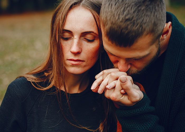 A man showing affection by kissing a woman's hand while she looks away, illustrating relationship icks men lose interest in.