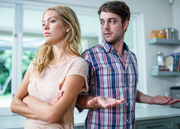 Man showing frustration while talking to woman with arms crossed, illustrating icks that make men lose interest in women.