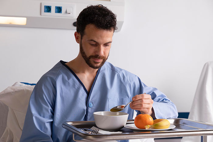 Man in hospital gown eating soup, illustrating caring for disabled brother after parents are gone and family conflict.